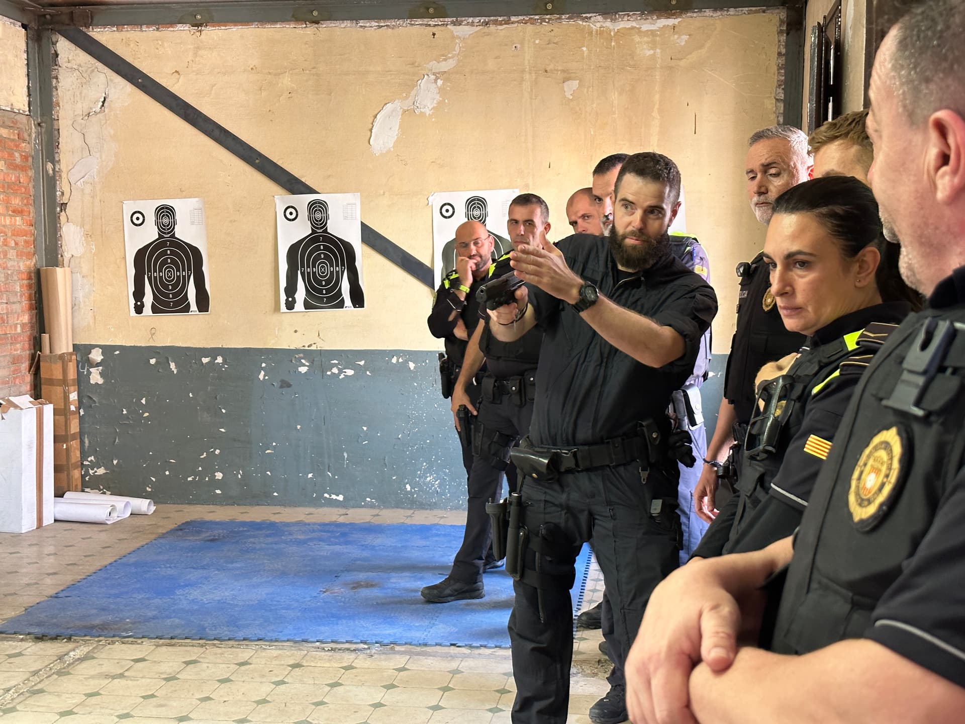 Formador ensenyant a un grup d'agents de policia com utilitzar una arma de foc.