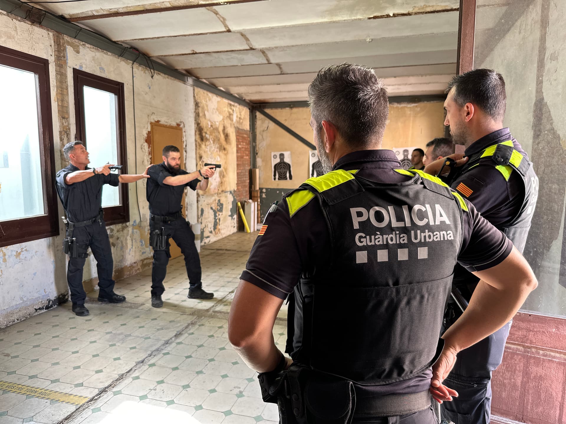 Formadors ensenyant a un grup d'agents de policia com realitzar una entrada i registre d'un immoble.